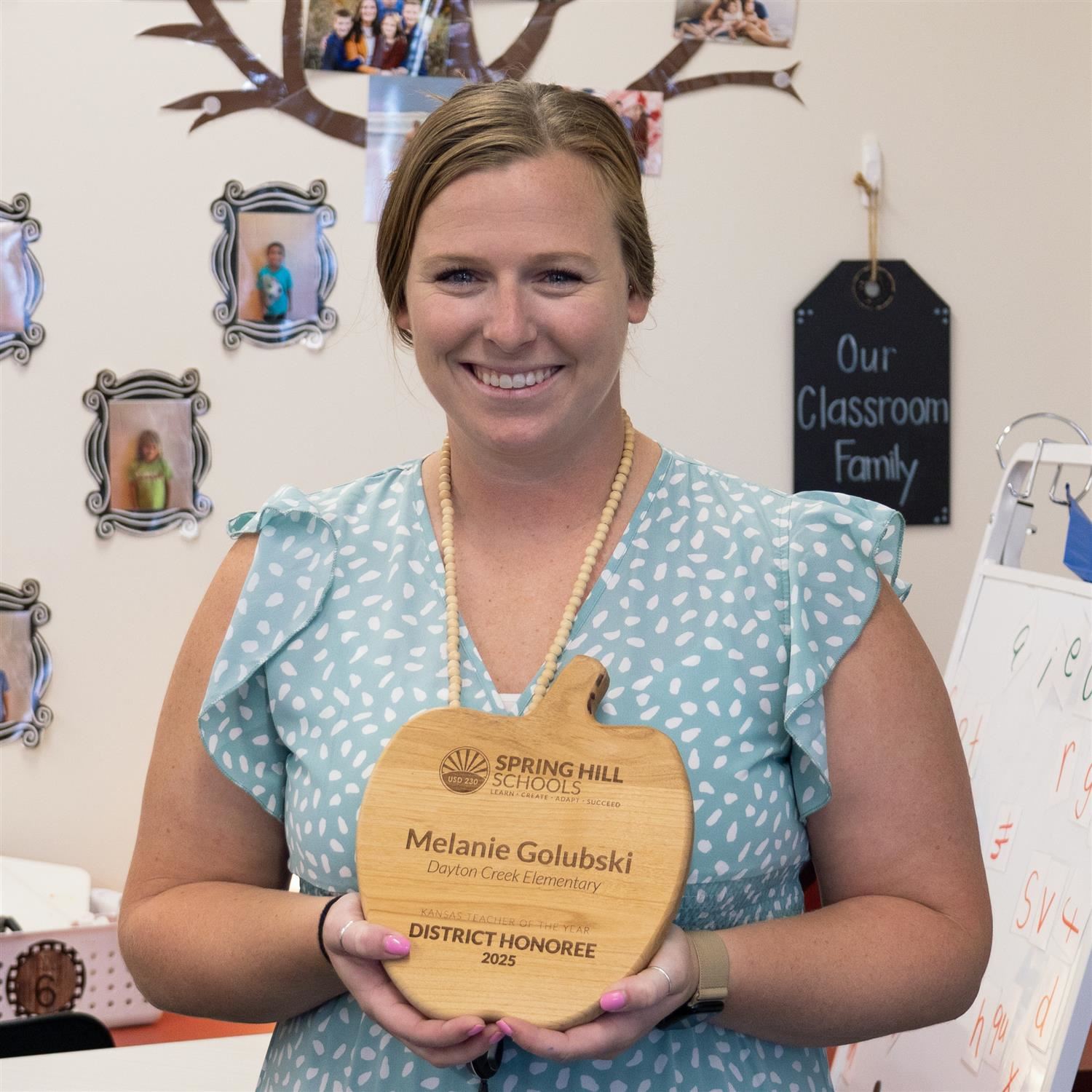 Melanie Golubski holding wooden, apple-shaped Teacher of the Year award plaque