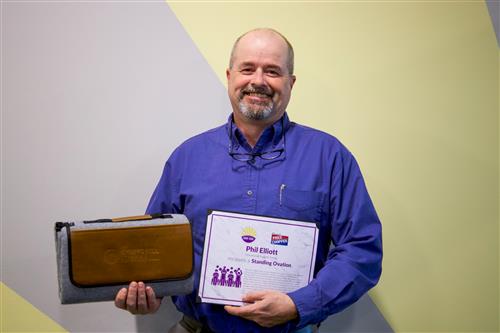 Phil Elliott smiling with Standing Ovation certificate and blanket prize