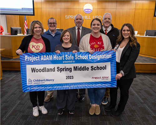 WSMS building team smiling in a group with Project ADAM banner