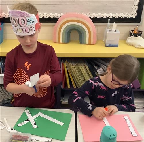 two students cutting and gluing an activity