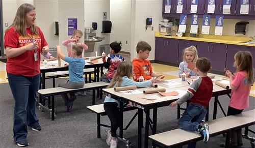 teacher standing, students sitting & constructing cottonwood tree craft