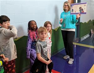 Teacher reading book page to students in hallway