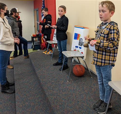 Three fourth graders giving their speeches to adults at the4th Grade Famous Kansan Wax Museum