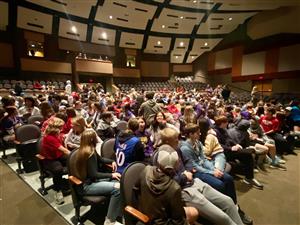 Students sit in auditorium waiting for performance.